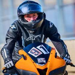 Rider in black Alpinestars leathers on an orange and black motorcycle; seen from the front with the orange and black motorcycle