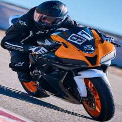 Rider in black Alpinestars leathers on an orange and black motorcycle; leaning through a corner from a different front three-quarter angle
