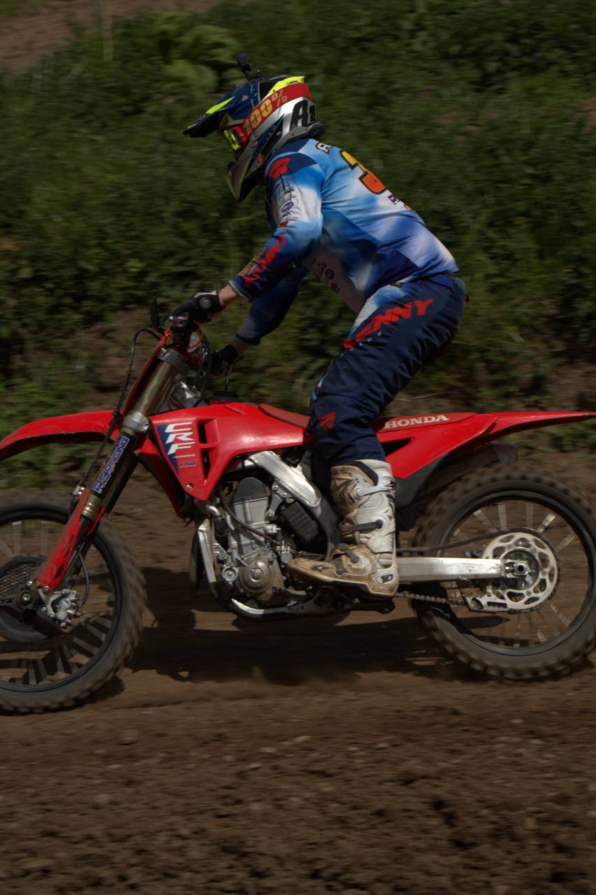 Rear-quarter view of a rider in blue kit on a red motorcycle.